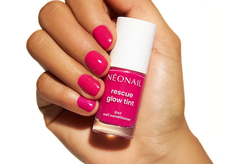Hand hält eine kleine pinke Nagellack-Flasche mit weißer Kappe, Flaschenaufdruck „NEONAIL rescue glow tint 3in1 nail conditioner“, Fingernägel sind passend in leuchtendem Pink lackiert