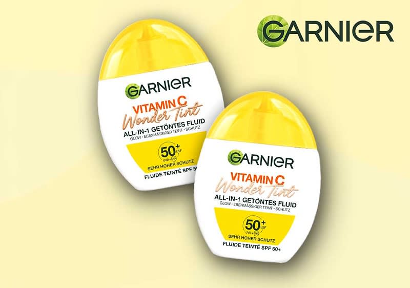 Zwei gelbe Flaschen des Garnier Vitamin C Wonder Tint Fluids mit der Aufschrift „ALL-IN-1 GETÖNTES FLUID“ und „SEMI-MATTE SCHUTZ FLUIDE TEINTE SPF 50+“. Oben rechts das Logo von Garnier
