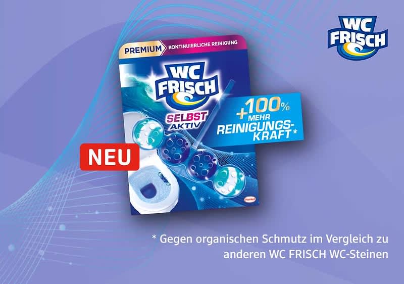 Packung eines WC Frisch WC-Steins in blau-lila Design mit der Aufschrift „WC FRISCH“, „SELBST AKTIV“, „+100% mehr Reinigungskraft*“ und rotem „NEU“-Label, im Vordergrund sichtbar ein weiß-blauer WC-Stein als Produktabbildung, unten die Auflösung des Sternchentextes: „Gegen organischen Schmutz im Vergleich zu anderen WC FRISCH WC-Steinen“
