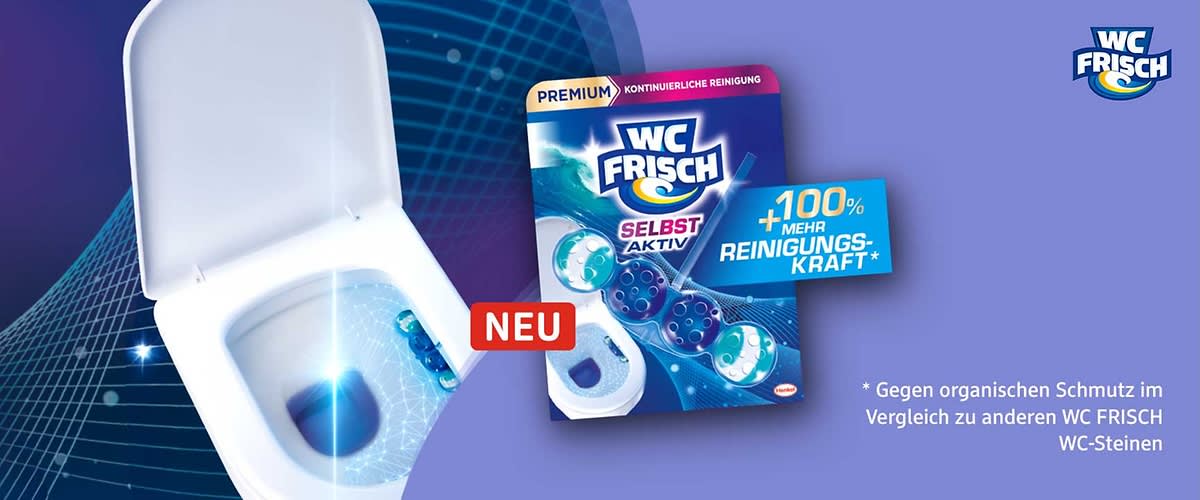 Packung eines WC Frisch WC-Steins in blau-lila Design mit der Aufschrift „WC FRISCH“, „SELBST AKTIV“, „+100% mehr Reinigungskraft*“ und rotem „NEU“-Label, im Vordergrund sichtbar ein weiß-blauer WC-Stein als Produktabbildung, unten die Auflösung des Sternchentextes: „Gegen organischen Schmutz im Vergleich zu anderen WC FRISCH WC-Steinen“