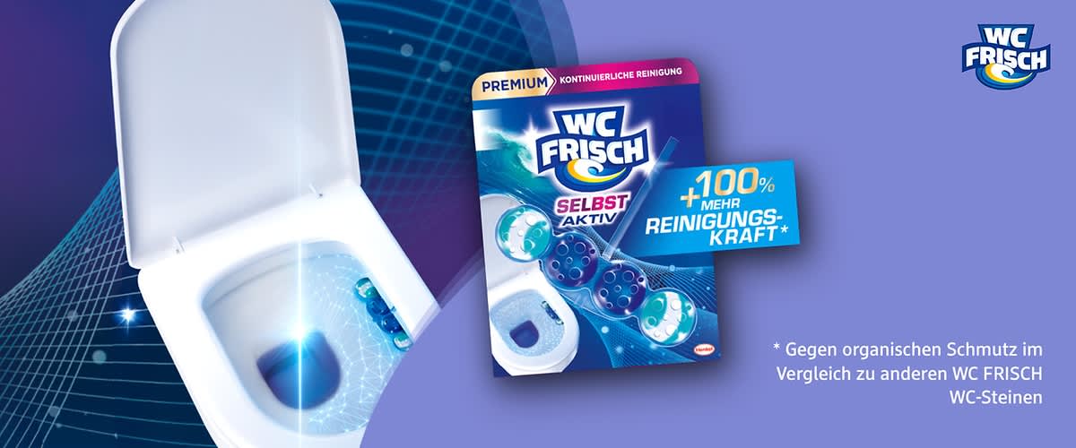 Packung eines WC Frisch WC-Steins in blau-lila Design mit der Aufschrift „WC FRISCH“, „SELBST AKTIV“, „+100% mehr Reinigungskraft*“ und rotem „NEU“-Label, im Vordergrund sichtbar ein weiß-blauer WC-Stein als Produktabbildung, unten die Auflösung des Sternchentextes: „Gegen organischen Schmutz im Vergleich zu anderen WC FRISCH WC-Steinen“