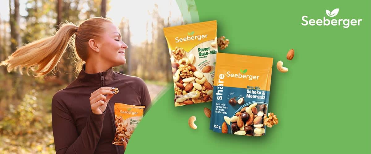 Zwei Seeberger Snack-Packungen auf grünem Hintergrund: links eine orange-gelbe Tüte mit der Aufschrift „Seeberger Power Nuss-Mix“ und Abbildung verschiedener Nüsse, rechts eine orange-blaue Tüte mit der Aufschrift „Seeberger share Schoko & Meersalz“ mit Abbildung von Nüssen und Schokoladenstücken, umgeben von einzelnen Mandeln, Cashewkernen und Walnussstücken, ober rechts das Seeberger-Logo ohne Punkt am Ende