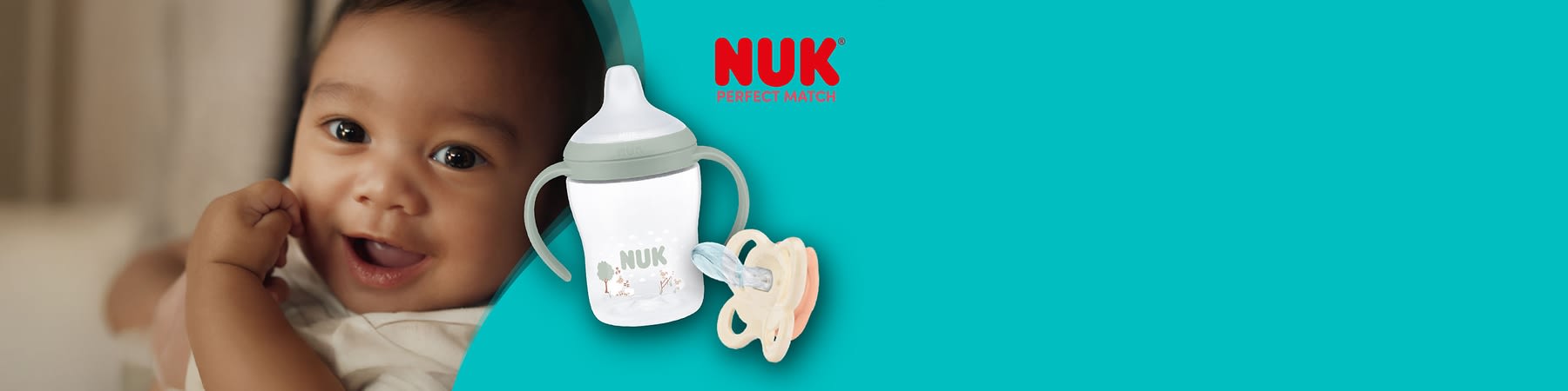 Weiße NUK Babytrinkflasche mit grünem Schraubring und zwei seitlichen Griffen sowie Motiv aus Bäumen und Tieren, daneben zwei beige und pastellrosa Nuckel nebeneinander auf hellblauem Hintergrund und rotes NUK-Logo oben rechts