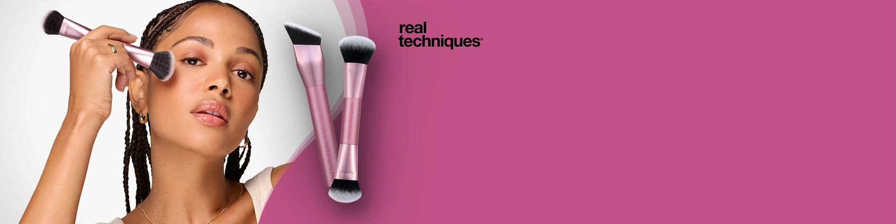 Zwei roségoldene Make-up-Pinsel der Marke Real Techniques mit schwarzen, dicht gebundenen Pinselköpfen liegen auf einem pinken Hintergrund, oben rechts das schwarze Logo „real techniques“