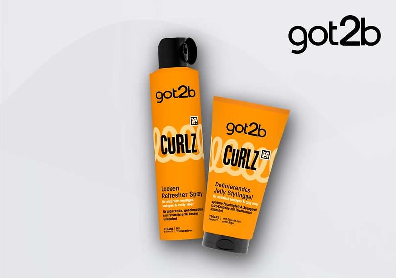 Zwei orangefarbene got2b Curlz-Haarpflegeprodukte auf hellgrauem Hintergrund: links eine hohe Sprühflasche mit schwarzem Sprühkopf und Aufschrift „Curlz Locken Refresher Spray“, rechts ein standfähiges Tubenbehältnis mit schwarzer Kappe und Aufschrift „Curlz Definierendes Jelly Stylinggel“, oben rechts zusätzlich das got2b-Logo ohne Punkt am Ende