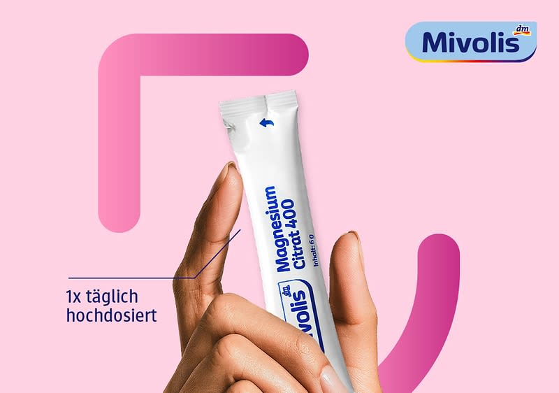 Hand hält eine einzelne weiß-rosa Sticksachet mit der blauen Aufschrift „Mivolis Magnesium Citrat 400“, daneben blauer Text „1x täglich hochdosiert“, im oberen rechten Eck das Mivolis-Logo vor rosa Hintergrund