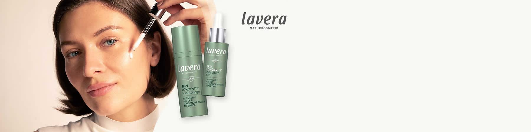 Zwei grüne Pflegeprodukte von Lavera: links eine stehende zylindrische Flasche mit der Aufschrift „lavera NATURKOSMETIK SKIN LONGEVITY Nachtpflege“ und rechts eine Flasche mit Pipette mit der Aufschrift „lavera SKIN LONGEVITY Schutz‑Serum“, rechts oben das Lavera‑Logo auf hellem Hintergrund