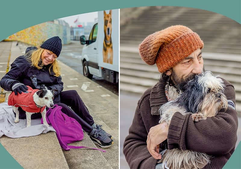 Links auf einer Treppenstufe sitzt eine Person mit dunkelblauer Mütze und Regenjacke und streichelt einen kleinen Hund mit weiß-schwarzem Fell; rechts eine andere Person mit orangefarbener Strickmütze und brauner Jacke hält einen kleinen langhaarigen Hund im Arm