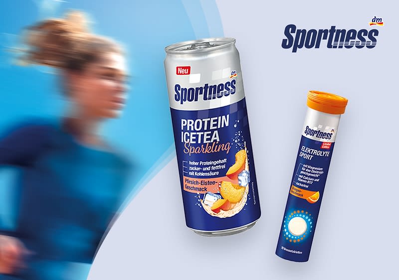 Zwei Sportness-Produkte vor hellblauem Hintergrund: links eine silberne Dose mit dunkelblauem Etikett und Aufschrift „Sportness Protein Ice Tea Sparkling“ sowie Bild von Pfirsich und Orange, rechts eine dunkelblaue Brausetabletten-Röhre mit orangem Deckel und Aufschrift „Sportness Elektrolyte Tab“; rechts oben das Sportness-Logo, links unscharfe Person in Sportkleidung im Hintergrund