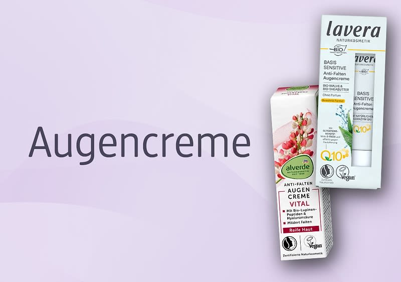 Zwei Produktpackungen für Augencreme nebeneinander vor hellem lilafarbenem Hintergrund, links eine weiße und rote Verpackung von alverde mit der Aufschrift „Anti-Falten Augen Creme Vital“, rechts eine weiße und mintfarbene Tube-Verpackung von lavera mit der Aufschrift „Basis Sensitiv Anti-Falten Augenpflege Q10“ und veganem Symbol, links neben den Produkten das Wort „Augencreme“ in großer Schrift