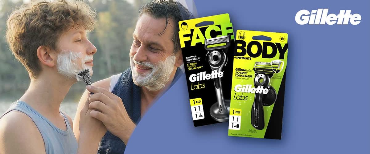 Zwei lächelnde Männer, einer rasiert den anderen mit einem Handrasierer im Freien, rechts zwei gelb-schwarze Produktverpackungen von Gillette Labs mit den Aufschriften „FACE“ und „BODY“ sowie das Gillette-Logo auf hellblauem Hintergrund