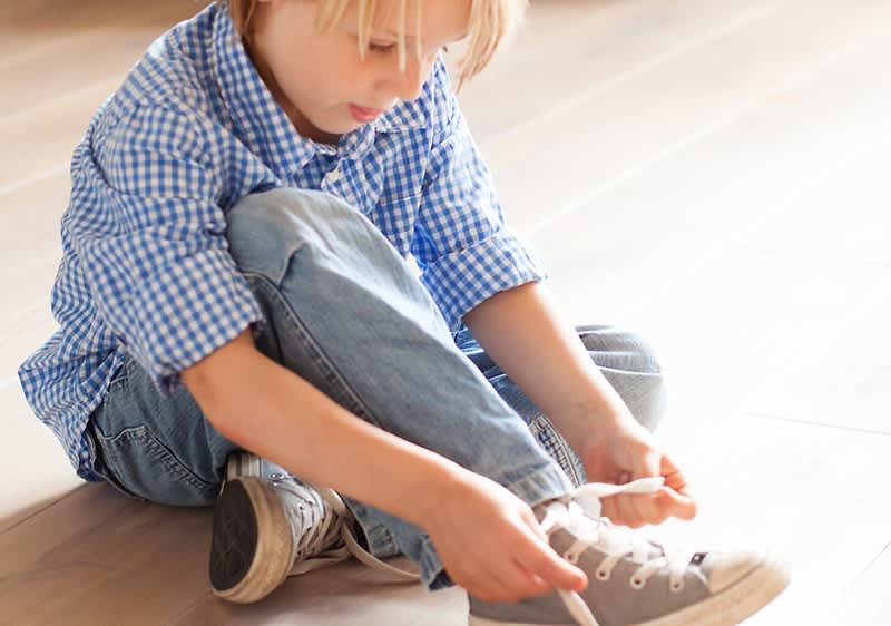 Kind zieht sich selbstständig Schuh an