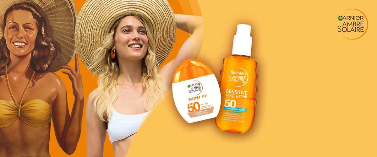 zwei orange-weiße Sonnenschutzprodukte von Garnier Ambre Solaire, links eine flache weiße Flasche mit orangem Deckel und Aufdruck „super uv 50“, rechts eine orange Sprühflasche mit Aufdruck „Sensitive Expert+ 50“ und Garnier-Logo, hellgelber Hintergrund