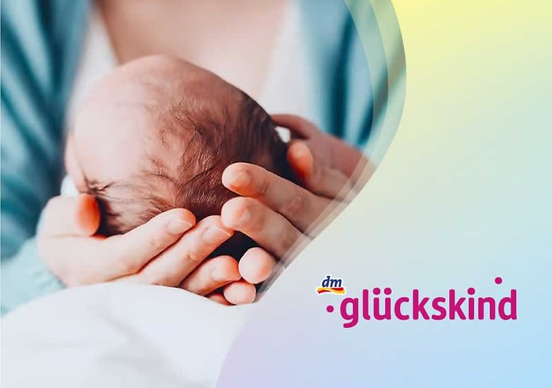Neugeborenes liegt in beiden Händen einer Person, im oberen rechten Bildteil das Logo „dm glückskind“