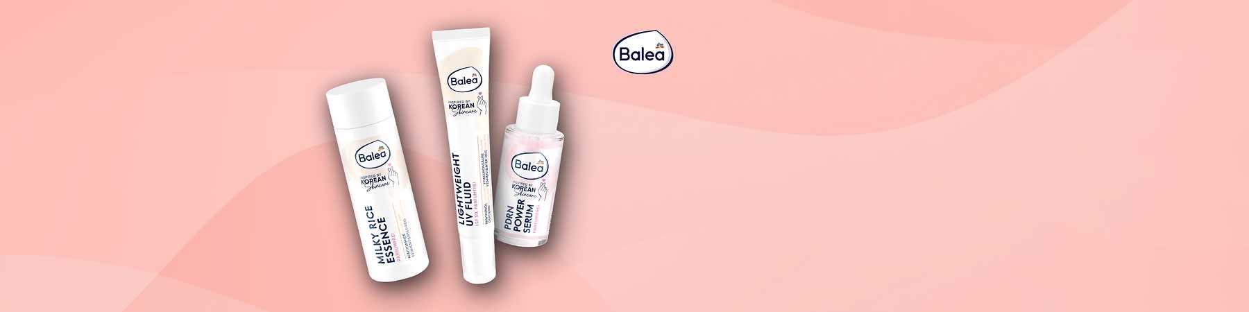 Drei Balea-Gesichtspflegeprodukte auf rosafarbenem Hintergrund: links eine weiße Flasche mit Aufschrift „Milky-Rice Essence“, in der Mitte eine Produktbox mit Logo und Schrift „PDRN Power Serum“, rechts eine Glasflasche mit Pipette und Etikett „PDRN Power Serum“