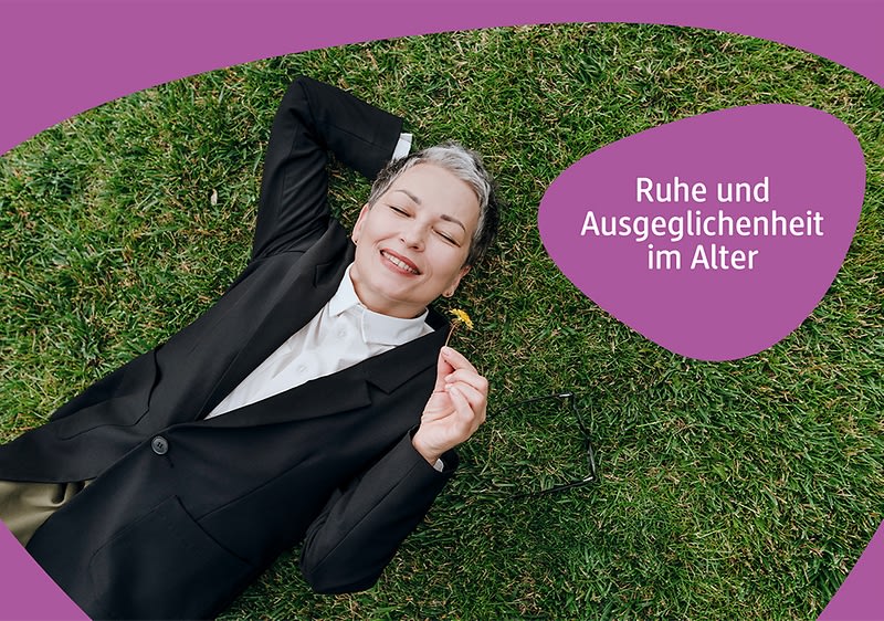 Person liegt auf Gras, trägt schwarzen Blazer und weiße Bluse, rechter Arm hinter dem Kopf, linke Hand hält eine Brille.