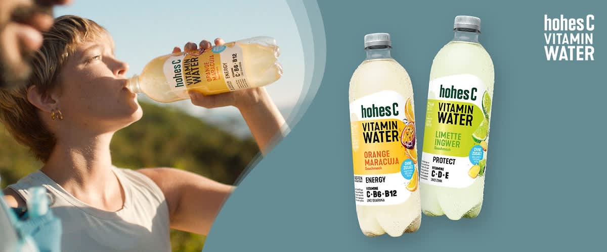 Zwei Flaschen Hohes C Vitamin Water vor einem blauen Hintergrund, die linke Flasche ist mit der Geschmacksrichtung Orange Maracuja und enthält die Vitamine C, B6 und B12, während die rechte Flasche die Geschmacksrichtung Limette Ingwer hat und die Vitamine C, D und E enthält, daneben sind auf der rechten Seite der Schriftzug hohes C Vitamin Water und auf den Flaschen sind die jeweiligen Früchte abgebildet