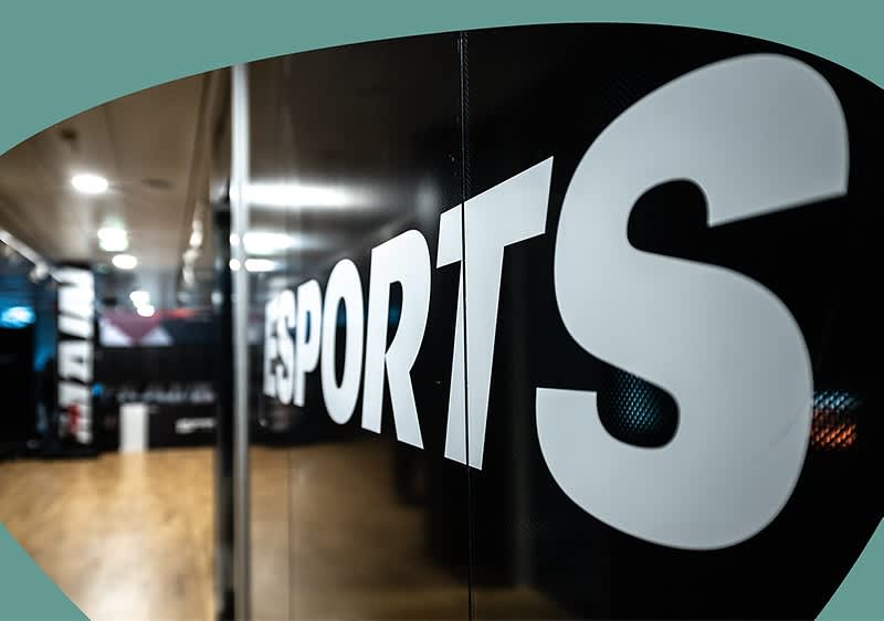 Großaufnahme einer schwarzen Glaswand mit weißem Schriftzug „ESPORTS“