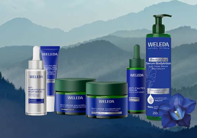 Mehrere dunkelblaue und grüne Weleda-Gesichtspflegeprodukte in unterschiedlicher Verpackungsform (Tropfflasche, Tiegel, Pumpspender, Tube) mit gut lesbarer Marke „WELEDA“ und Produktbeschriftungen wie „Anti-Falten“ und „Revitalizing Serum Bodylotion“ vor stilisiertem Berghintergrund