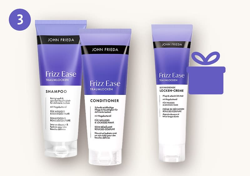 Drei lilafarbene Tuben John Frieda Frizz Ease Traumlocken: links Shampoo, Mitte Conditioner, rechts definierende Locken-Creme, zusätzlich lila Geschenk-Symbol oben rechts