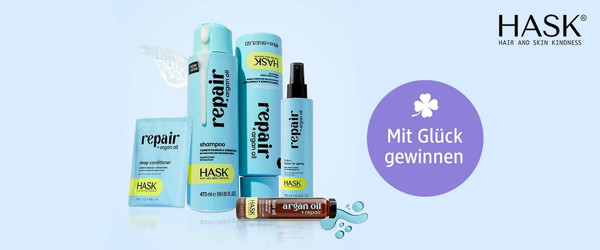 Mehrere hellblaue HASK Haarpflegeprodukte mit Aufschrift „repair + argan oil“: Shampooflasche, Spray, Tube, Sachet und kleine Ampulle, rechts oben schwarz das HASK-Logo, rechts ein lilaner Kreis mit weißer Blütengrafik und Text „Mit Glück gewinnen“