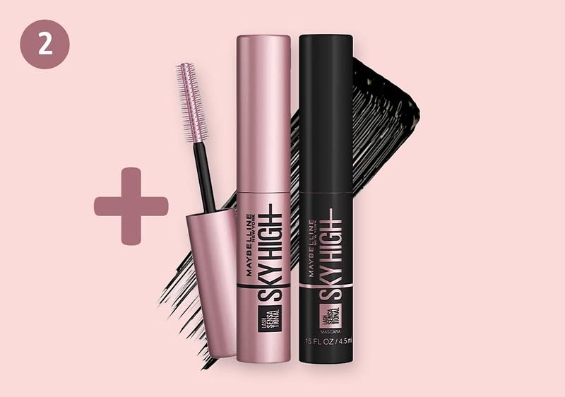 zwei Maybelline Sky High Mascaras nebeneinander, links rosa Hülse, rechts schwarze Hülse mit schwarzem Mascara-Strich im Hintergrund und einem Pluszeichen links oben
