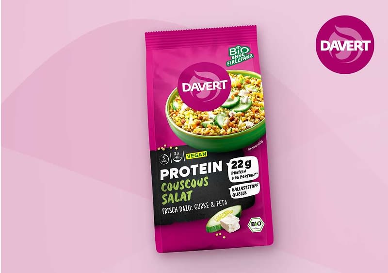 Rosafarbene Verpackung von Davert Protein Couscous Salat, vorne Bild einer grünen Schüssel mit Couscous, Aufdruck „Protein Couscous Salat“, Hinweise „vegan“, „22 g Protein pro Portion“, „Ballaststoffe“ sowie kleiner Text „frisch dazu: Gurke & Feta“ und Bio-Siegel