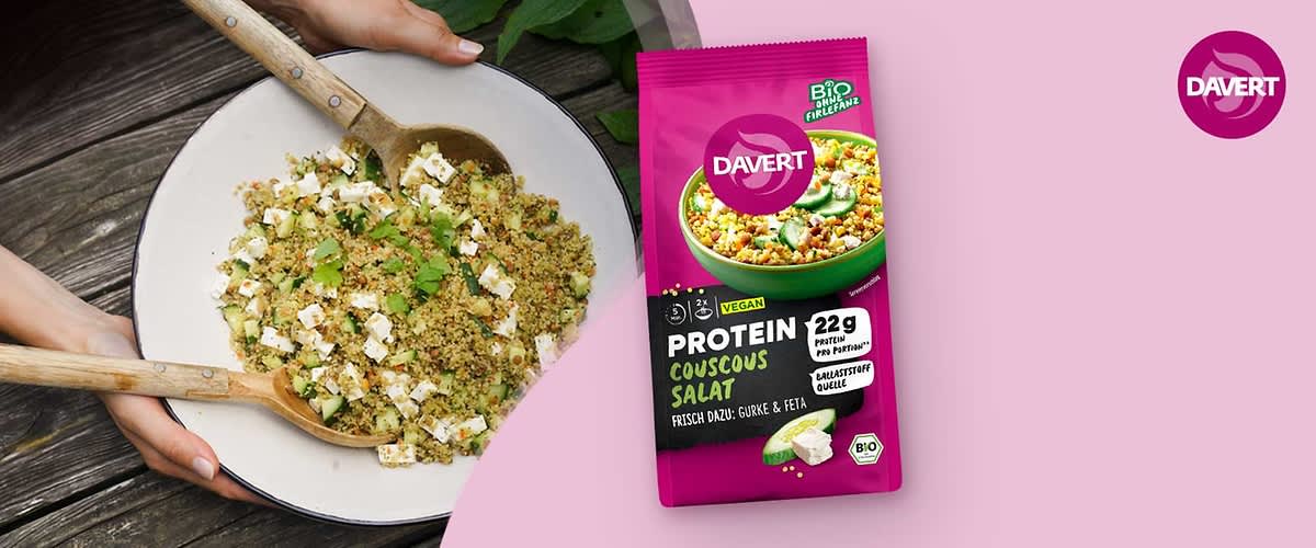 Rosafarbene Verpackung von Davert Protein Couscous Salat, vorne Bild einer grünen Schüssel mit Couscous, Aufdruck „Protein Couscous Salat“, Hinweise „vegan“, „22 g Protein pro Portion“, „Ballaststoffe“ sowie kleiner Text „frisch dazu: Gurke & Feta“ und Bio-Siegel