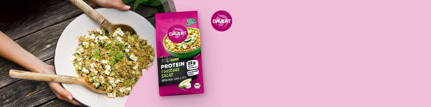 Magentafarbene Verpackung von Davert Protein Couscous Salat, Aufschrift „22 g Protein“, „Vegan“, Bild einer Schüssel mit Couscous, Gurkenscheiben und Feta, zusätzlicher Text „frisch dazu: Gurke & Feta“