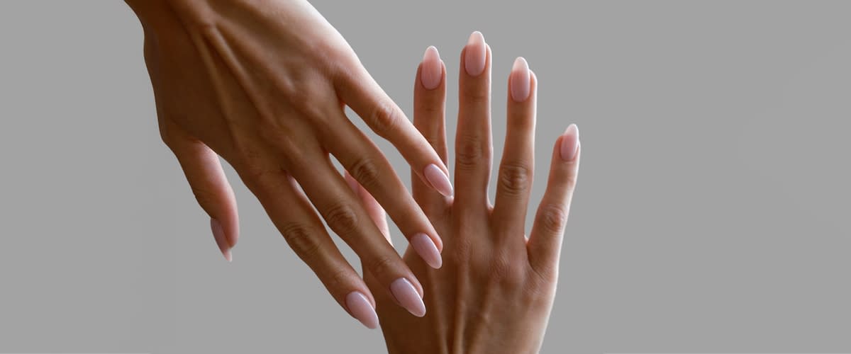 Zwei weiblich wirkende Hände mit hellrosa, mandelförmig gefeilten Gelnägeln, eine Hand leicht über der anderen gehalten