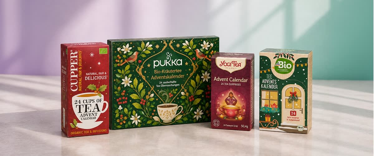 Vier Adventskalender mit Tee in Reihenfolge von links nach rechts: rote Packung Cupper 24 Cups of Tea Advent Calendar, grün gemusterte Packung pukka Bio-Kräutertee Adventskalender, rote Packung Yogi Tea Advent Calendar, beige-grüne Packung Bio Tee Advents Kalender. Bild mithilfe von KI erstellt