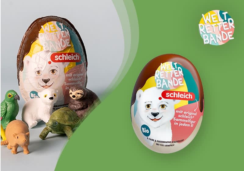 Schleich Überraschungsei mit Aufschrift „Weltretter Bande“, abgebildet als weiß-braunes Ei mit Eisbären-Motiv und blauem Bio-Logo, daneben mehrere kleine Tierfiguren auf hellem Untergrund und links ein weiteres geöffnetes Ei mit verdecktem Bereich