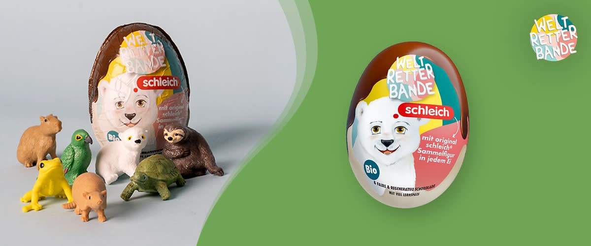 Schleich Überraschungsei mit Aufschrift „Weltretter Bande“, abgebildet als weiß-braunes Ei mit Eisbären-Motiv und blauem Bio-Logo, daneben mehrere kleine Tierfiguren auf hellem Untergrund und links ein weiteres geöffnetes Ei mit verdecktem Bereich