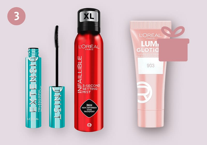 Drei L’Oréal-Produkte auf hellem Hintergrund: links offene türkise Mascara-Verpackung mit Bürste und Aufschrift „EXTENSIONIST“, in der Mitte rote Sprühdose „L’Oréal Infallible 3-Second Setting Mist“, rechts rosa Tube „Lumi Glotion 903“ mit Geschenk-Symbol oben rechts