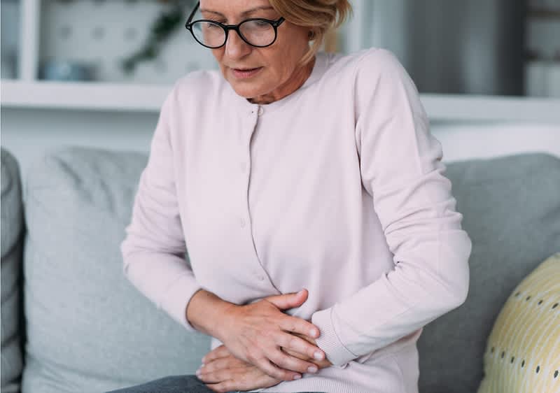 Frau legt ihre Hände auf den Unterbauch