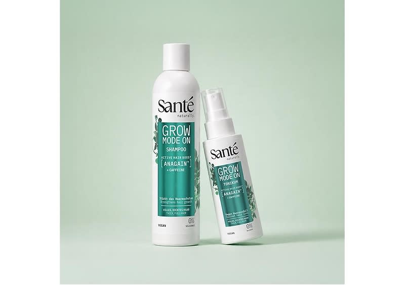 Zwei weiße Pflegeflaschen der Marke Sante mit grünem Etikett und Schriftzug „GROW MODE ON“, links eine hohe Shampoo-Flasche, rechts ein kleinerer Pumpspray-Tonikum mit Hinweis „ANAGAIN™ + CAFFEINE“