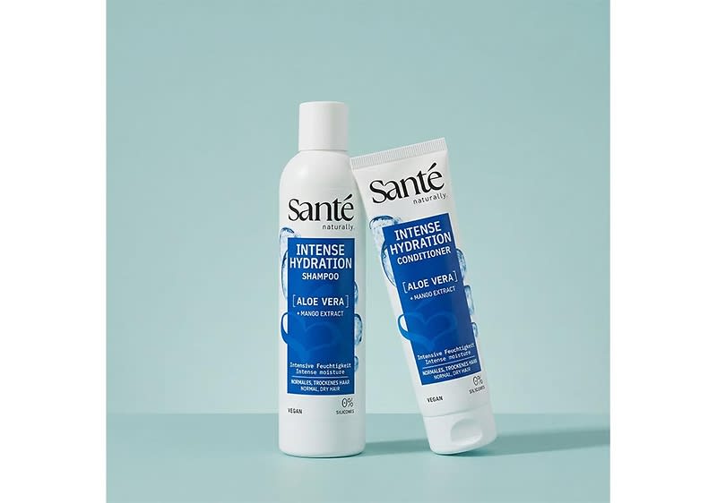 weiße Shampoo- und Conditioner-Flasche der Marke Sante mit blauem Etikett „Intense Hydration“ und Zusatz „Aloe Vera“, Conditioner liegt leicht schräg am Shampoo