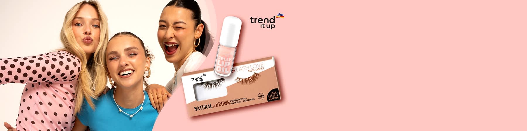Drei junge Frauen posieren eng nebeneinander, rechts daneben Lippenstift-Glasflakon mit der Aufschrift „JELLY LIP GLOSS“ und darunter Verpackung falscher Wimpern „BIG LASH LOVE“ in der Farbbezeichnung „NATURAL in BROWN“, oben rechts Logo „trend it up“