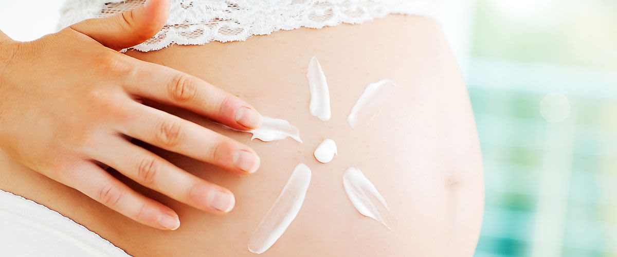 Blume aus Creme auf schwangerem Bauch