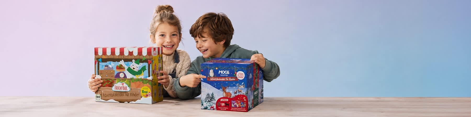 Zwei Kinder sitzen an einem Tisch und halten je einen Adventskalender, links ein bunter „FruchtBar Adventskalender für Kinder“ mit Marktstand-Design, rechts ein blauer „Mogli Adventskalender für Kinder“ mit winterlicher Rentier-Illustration. Bild mithilfe von KI erstellt