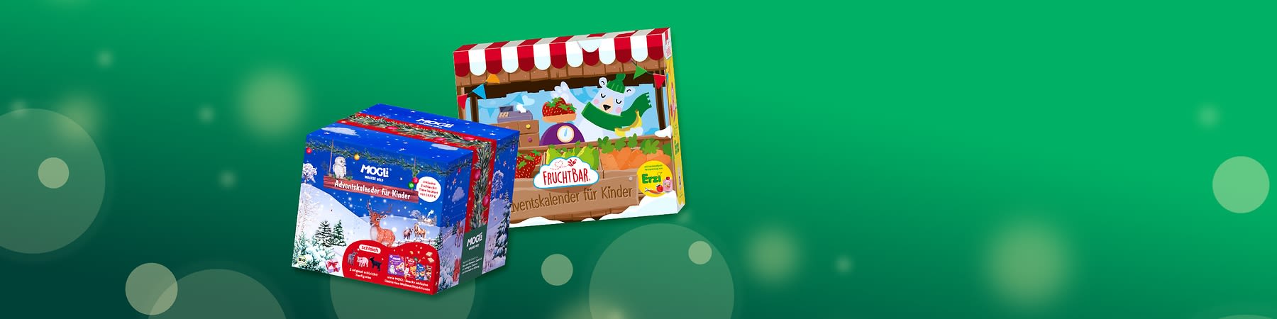 Zwei Adventskalender-Verpackungen für Kinder: vorn links blauer Adventskalender der Marke MOGL mit Winterwald-, Rentier- und Weihnachtsmotiv, hinten rechts bunter Adventskalender der Marke FruchtBar mit Marktstand-, Obst- und Tierillustration