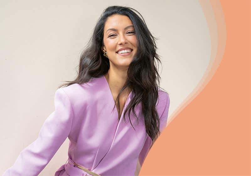 Rebecca Mir in rosa-blau schimmerndem Blazer lächelnd