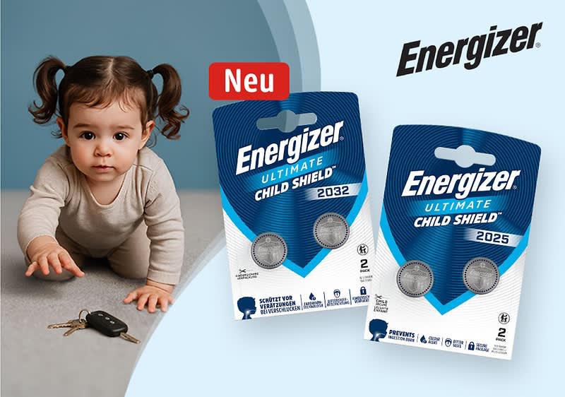 Kleines Kind krabbelt nach Autoschlüssel auf Boden; rechts zwei bläuliche Packungen Energizer Ultimate Child Shield Knopfzellen (Modelle 2032 und 2025) mit rotem „Neu“-Label und Energizer-Logo