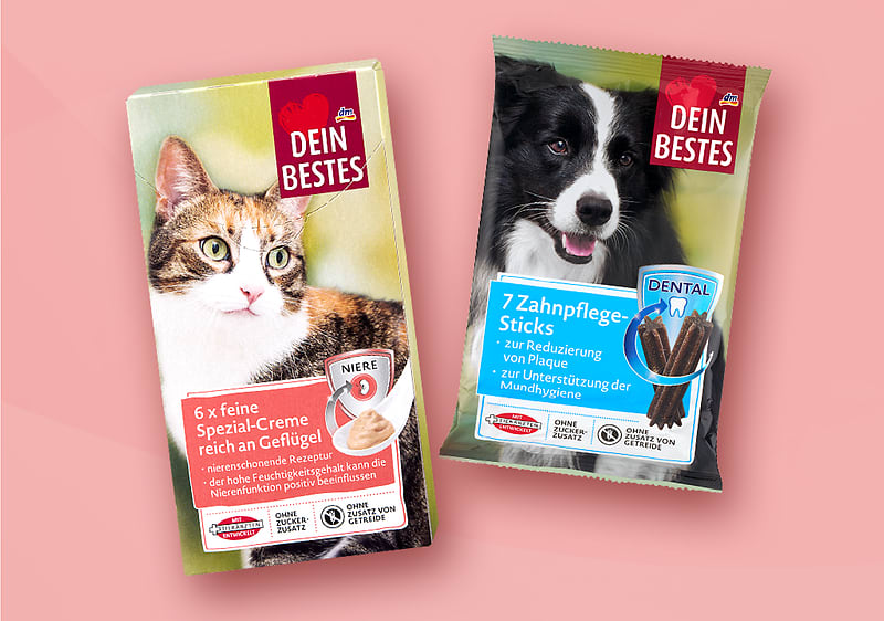 Zwei Produktverpackungen der Marke „Dein Bestes“: links eine rechteckige Katzenfutter-Schachtel mit Katzenbild und Schriftzug „6 x feine Spezial-Creme reich an Geflügel“ sowie Hinweis „Niere“, rechts eine Tüte Hundesnack mit Hunde-Bild und Aufdruck „7 Zahnpflege-Sticks“ und blauem Zahn-Symbol. Bild mithilfe von KI erstellt