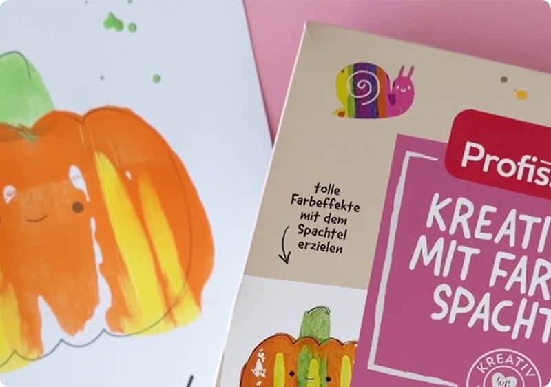A gezeichneter orangefarbener Kürbis links auf weißem Papier und rechts eine Produktverpackung mit Teilaufschrift „KREATIV MIT FARBE SPACHTEL“, kleinem buntem Schnecken-Logo und Texthinweis „tolle Farbeffekte mit dem Spachtel erzielen“