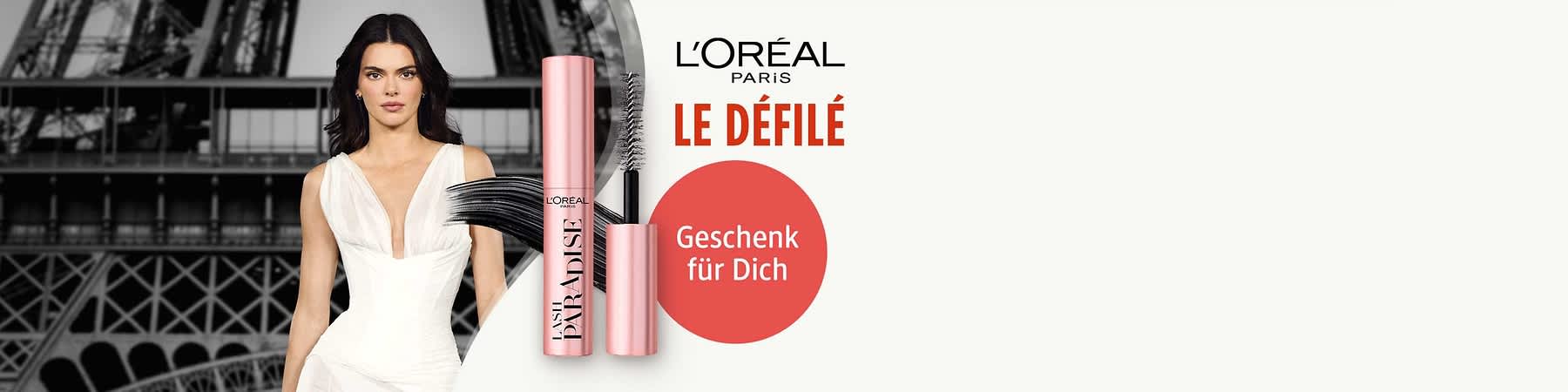 rosa Mascara-Roulette mit geöffnetem Bürstenstab und schwarzem Wisch, daneben roter Kreis mit weißem Text „Geschenk für Dich“ und oben rechts L'Oréal Paris Le Défilé Schriftzug