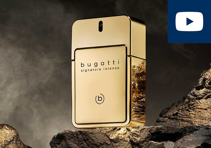 Goldfarbene Parfümflasche in rechteckiger Form mit Aufdruck „bugatti signature intense“ und rundem Markenlogo, auf dunklem, felsigem Hintergrund, oben rechts ein kleines blaues Play-Symbol