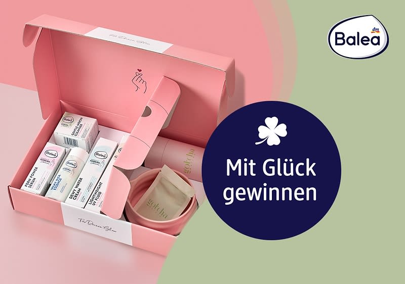 rosa Geschenkbox geöffnet mit mehreren Balea-Produktverpackungen, einem kleinen Becher und einzelnen Pads, rechts ein dunkelblauer Kreis mit weißer Kleeblattgrafik und dem Text „Mit Glück gewinnen“, oben rechts das Balea-Logo