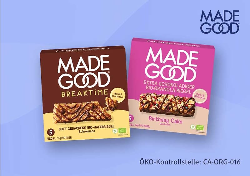 Zwei Produktverpackungen von MADE GOOD: links braune Packung „MORNINGS“ mit Aufschrift „Soft gebackene Bio-Haferriegel Schokolade“ und rechts pinke Packung „EXTRA SCHOKOLADIGER BIO-GRANOLA RIEGEL Birthday Cake“, jeweils mit Bild eines Riegels und Bio- sowie Vegan-Symbolen, im Hintergrund oben rechts großes MADE GOOD-Logo