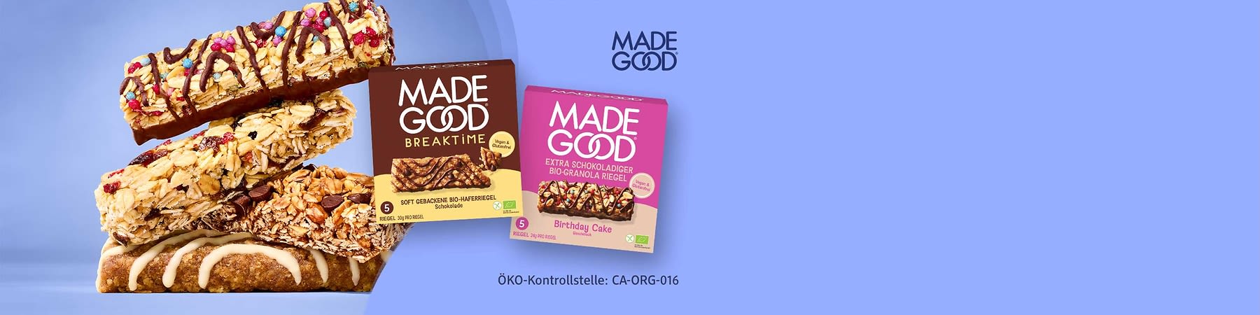 Zwei Produktverpackungen von MADE GOOD: links braune Packung „MORNINGS“ mit Aufschrift „Soft gebackene Bio-Haferriegel Schokolade“ und rechts pinke Packung „EXTRA SCHOKOLADIGER BIO-GRANOLA RIEGEL Birthday Cake“, jeweils mit Bild eines Riegels und Bio- sowie Vegan-Symbolen, im Hintergrund oben rechts großes MADE GOOD-Logo
